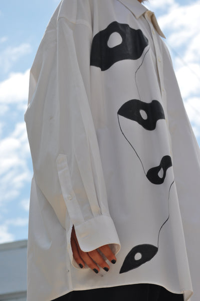 ZOOMED IN IMAGE OF HAND PAINTED MOTIF ON OVERSIZED WHITE BUTTON DOWN SHIRT.