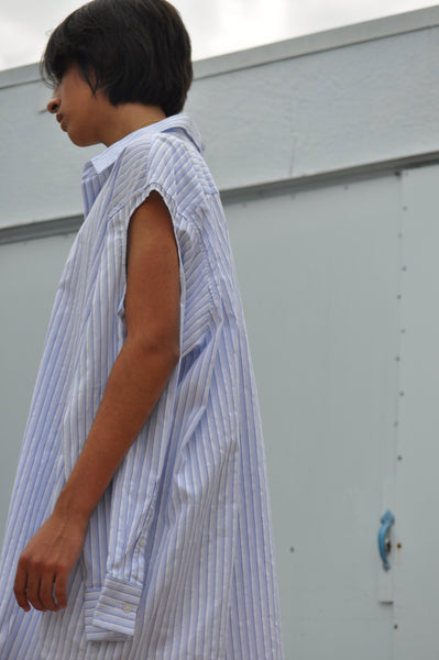 SIDE VIEW OF OVERSIZED BUTTON DOWN SHIRT WITH SLEEVE CUT OUT.