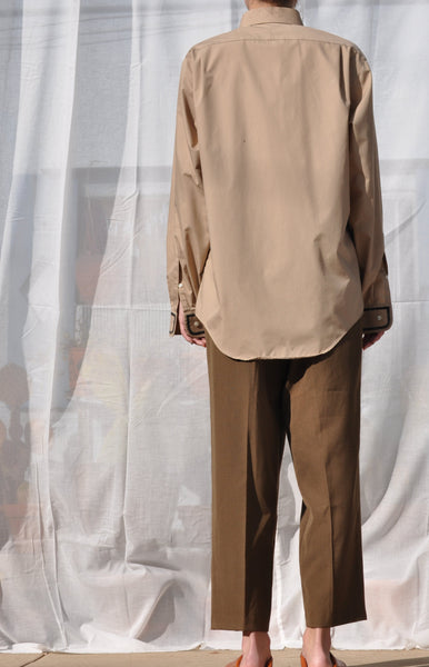 BACK IMAGE OF TAN BUTTON DOWN SHIRT STYLED WITH DARK OLIVE CROPPED PANTS.