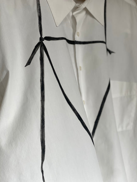 CLOSE UP OF HAND PAINTED TIE DETAILS IN BLACK. HAND CRAFTED ON SECONDHAND WHITE BUTTON DOWN SHIRT.