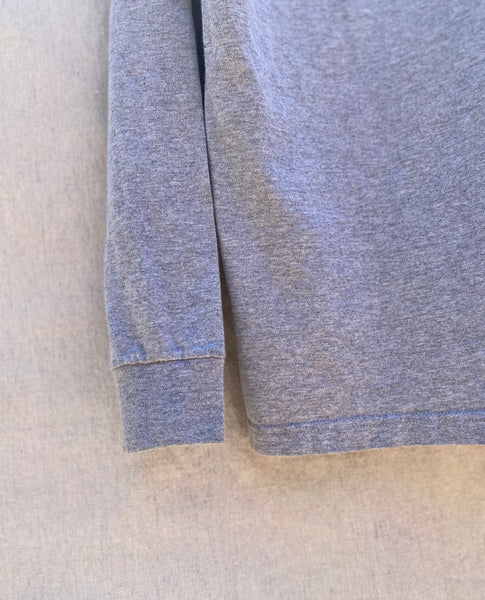 CLOSE UP OF BOTTOM RIGHT HEM AND CUFF OF LONG SLEEVE TEE IN HEATHER GREY.