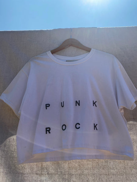 CLOSE UP VIEW OF FRONT CROPPED SHIRT WITH PUNK ROCK EMBROIDERY ON IT.