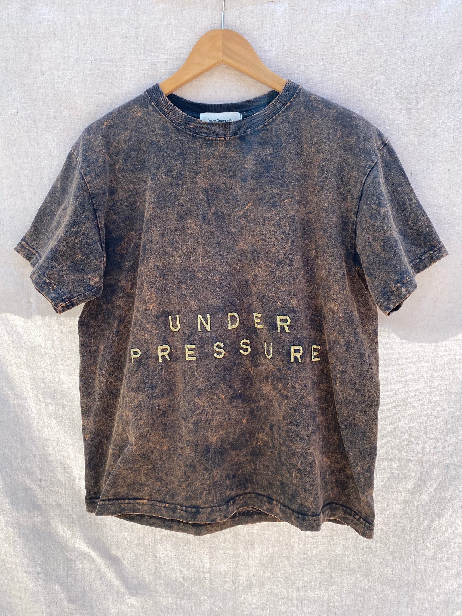 FULL FRONT VIEW OF T-SHIRT WITH UNDER PRESSURE EMBROIDERY.
