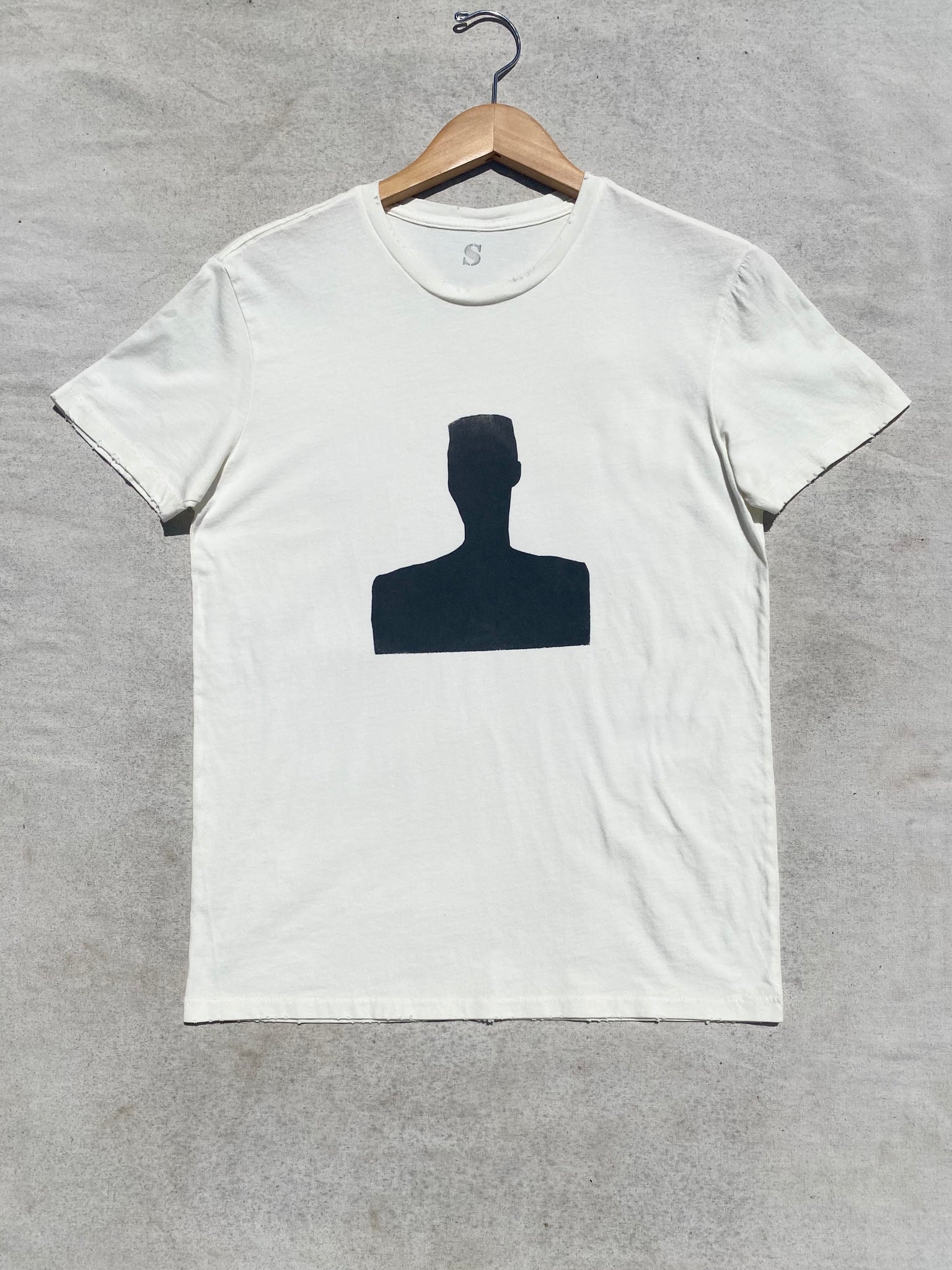 FRONT IMAGE OF DISTRESSED  CREAM T-SHIRT SILK SCREENED WITH BLACK MOTIF.