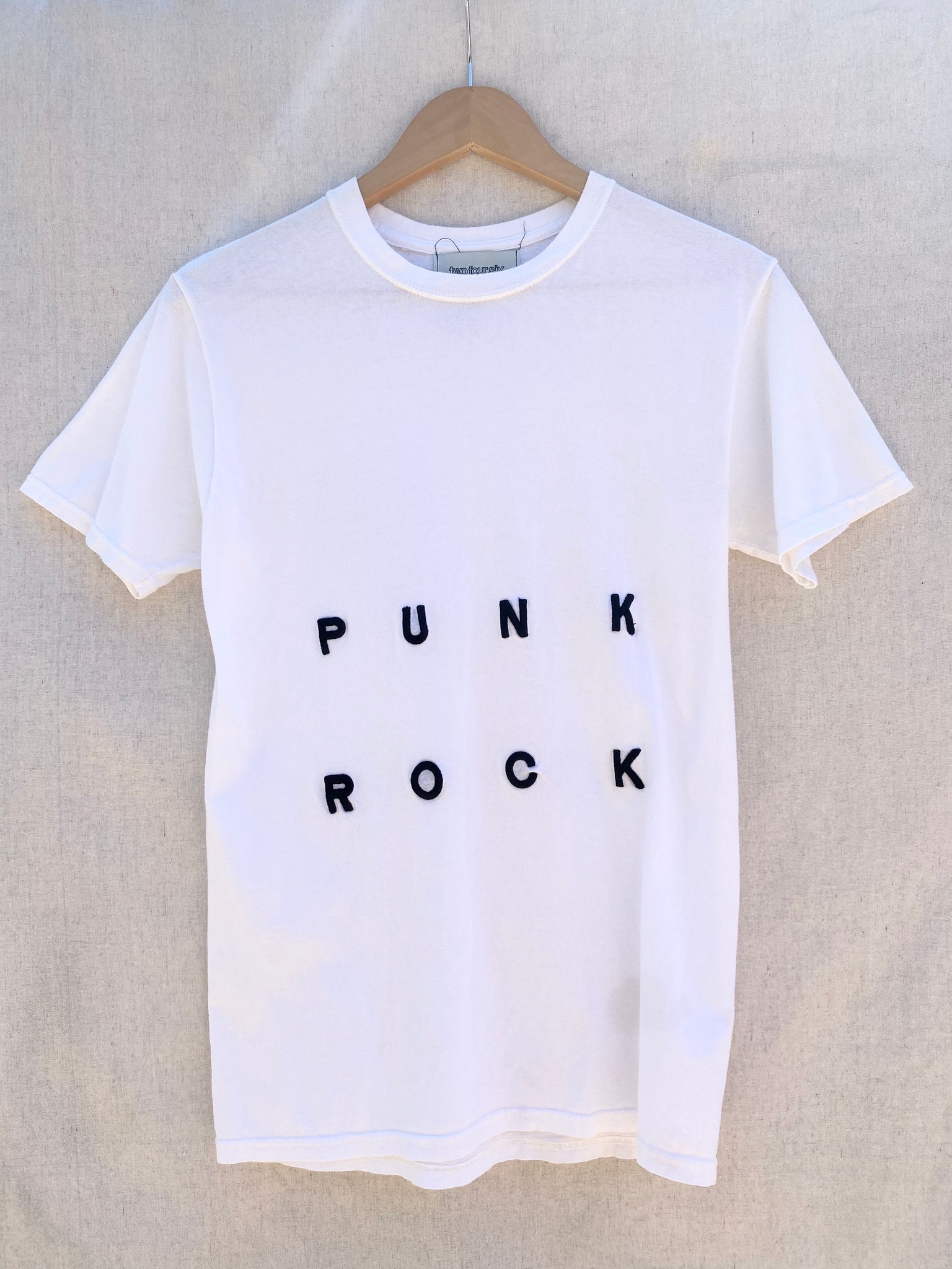 IMAGE OF WHITE T-SHIRT FRONT VIEW WITH PUNK ROCK EMBROIDERY IN BLACK.