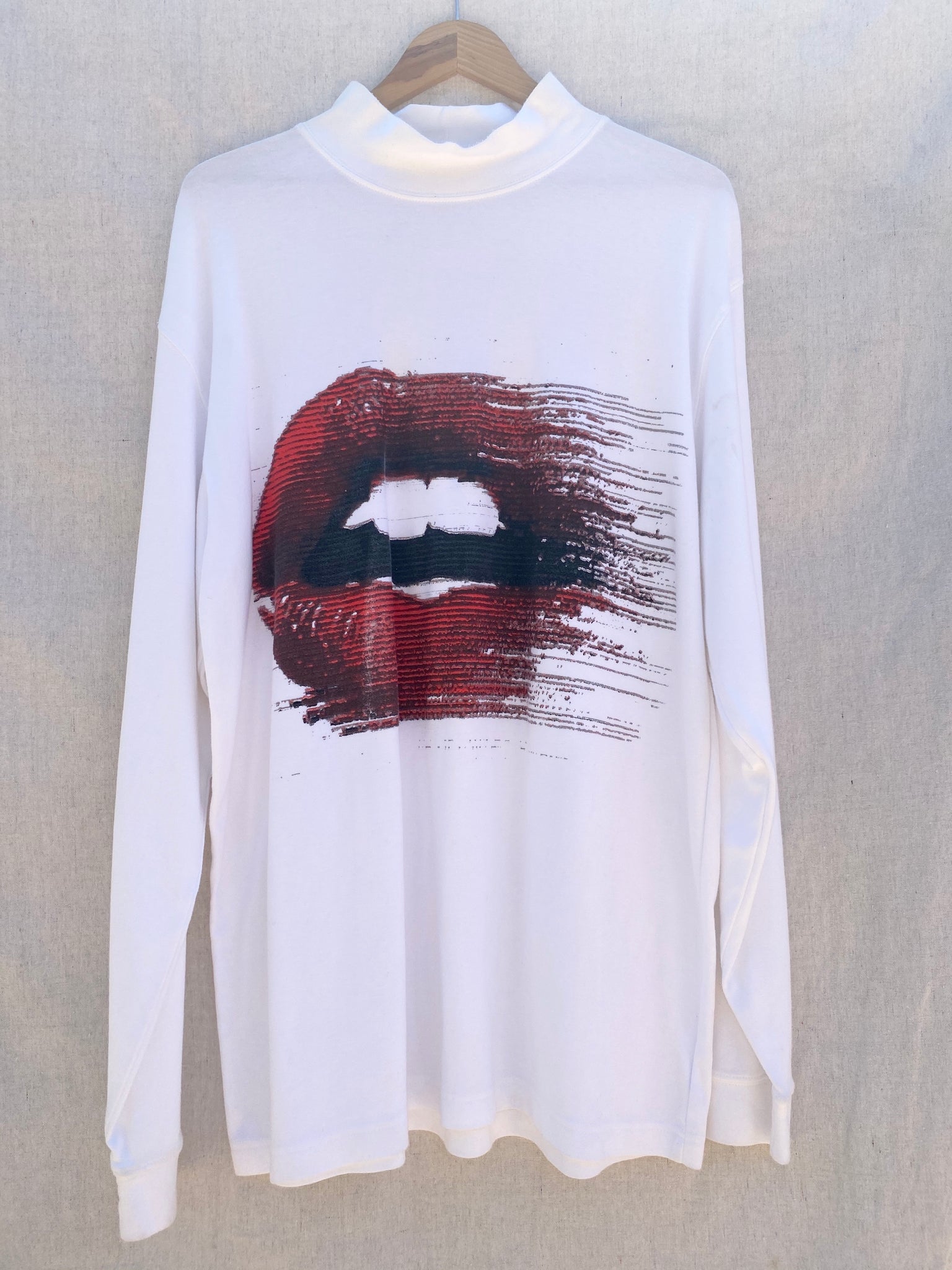 FONT VIEW OF WHITE LONG SLEEVES TEE WITH MOCK NECK. PRINTED WITH MOUTH WITH RED LIPS.