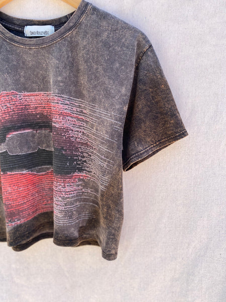 CLOSE UP VIEW OF FRONT LEFT NECK AND SLEEVE. HALF OF LIP PRINT IS VISIBLE.