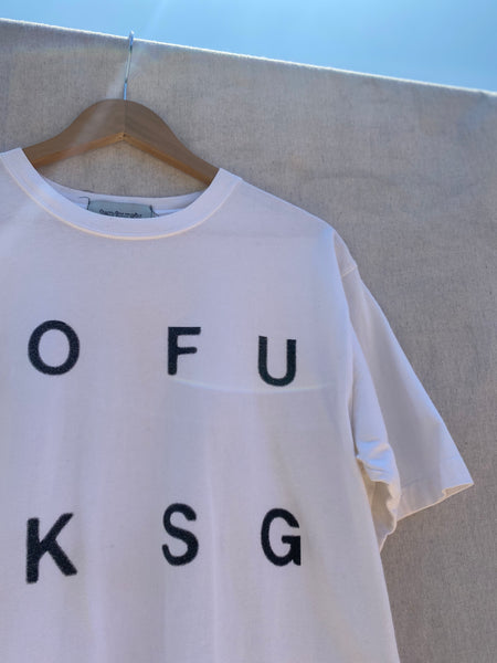 ZOOMED IN VIEW OF T-SHIRT'S UPPER FRONT LEFT. PRINTED LETTERS  OFUKSG ALSO VISIBLE.
